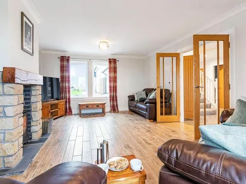 Cottage lounge with stone fireplace, leather sofas and wooden floor