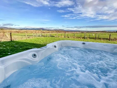 Hot tub in garden with countryside views and fenced lawn