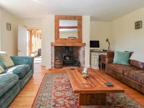 Cottage lounge with wood-burning stove, sofas and wooden coffee table