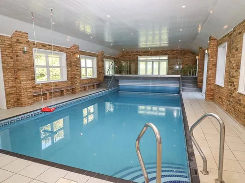 Indoor cottage pool with brick walls and metal handrails