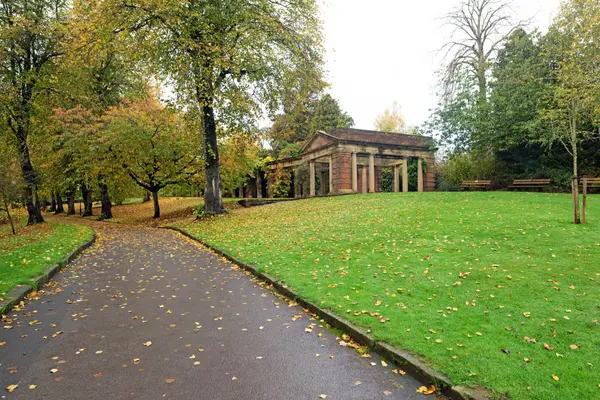 A tree-lined path with autumn leaves leads to a classical temple in Valley Gardens, Harrogate