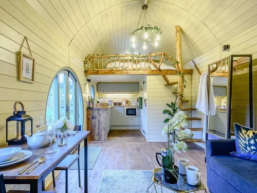 Lodge interior with kitchen, mezzanine bed, dining table and wooden spiral stairs