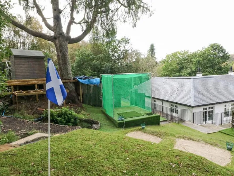 Heatherbank garden with golf practice net, putting green and Scottish flag