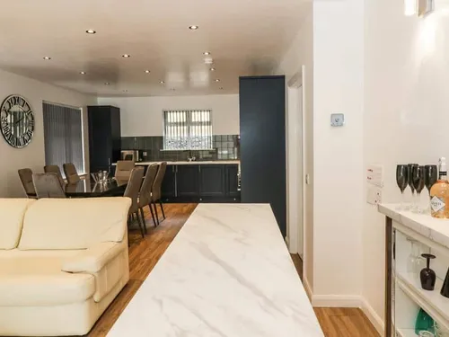 Open-plan cottage kitchen and dining area with a drinks shelf and cream sofa.