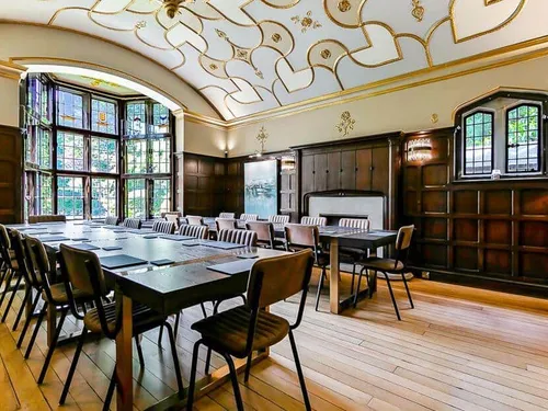 Cottage dining room with long table, chairs and stained glass bay window
