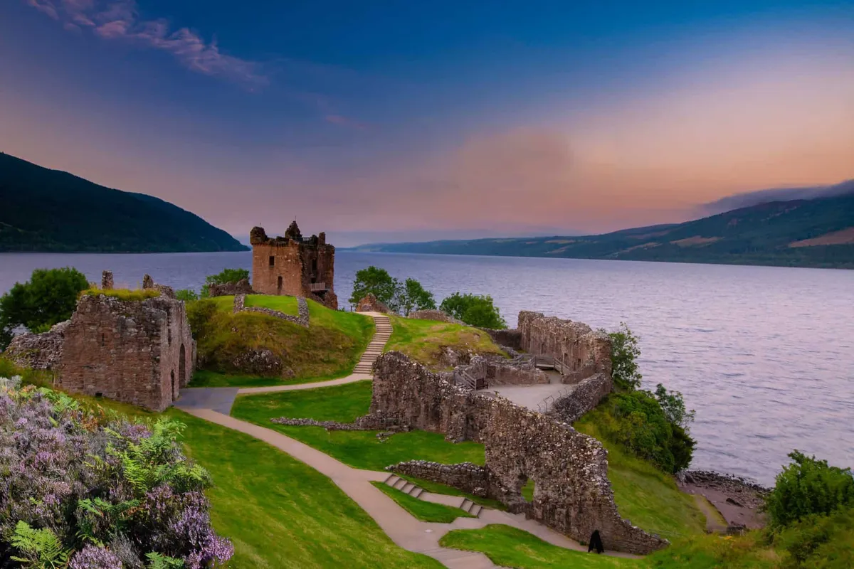 Sunset painting the sky purple over the ruins of Urquhart Castle on the banks of Loch Ness.