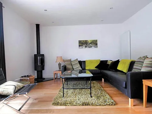 Cottage living room with corner sofa, glass coffee table and log burner