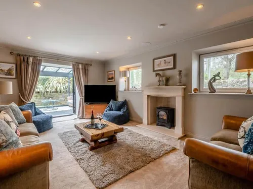Cottage lounge with fireplace, TV and doors opening to patio garden
