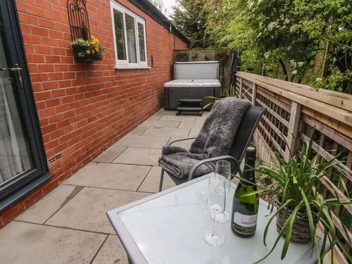 Lodge patio with hot tub, chair and table with wine and glasses
