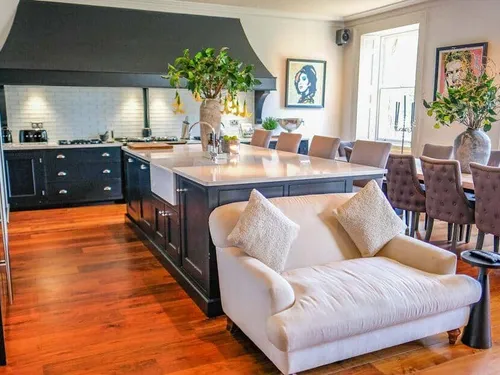 Cottage kitchen with central island, dining table and cream sofa in foreground