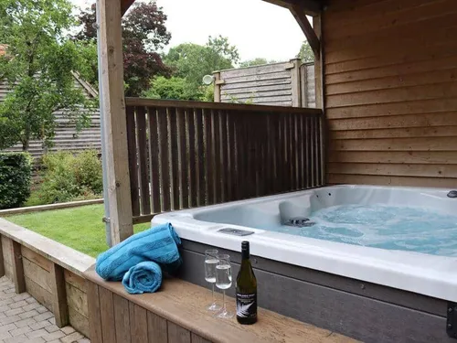 Cottage patio with hot tub, towels, wine bottle and glasses on wooden decking