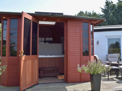 Lodge cabin with open wooden doors revealing indoor hot tub on decking area