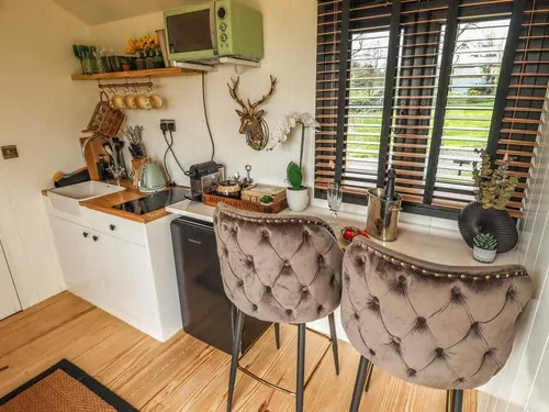 Lodge kitchen with breakfast bar and two upholstered chairs by window blinds