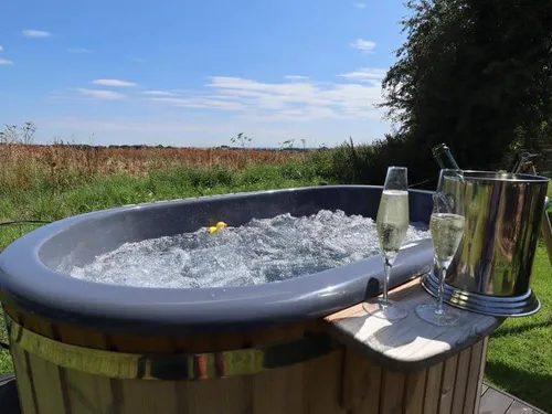Lodge hot tub with champagne glasses and ice bucket on wooden side table