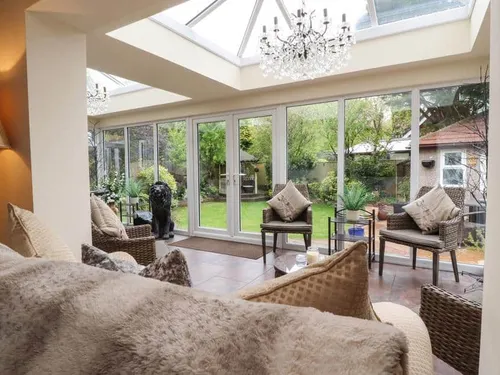 Cottage conservatory with wicker chairs and garden view through glass doors