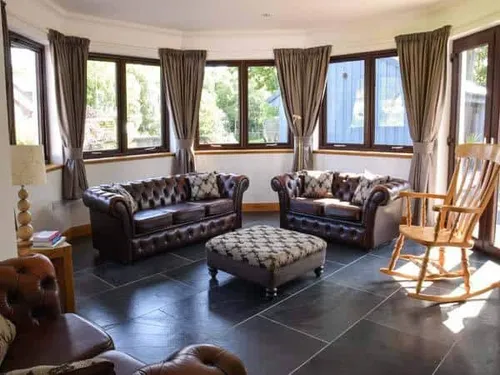 Cottage lounge with leather sofas, footstool and rocking chair by bay windows