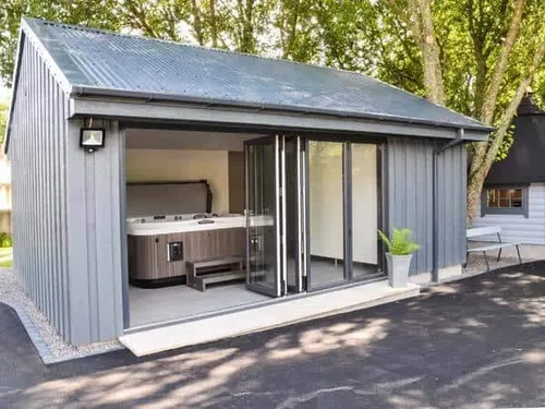 Cottage outbuilding with open glass doors and indoor hot tub