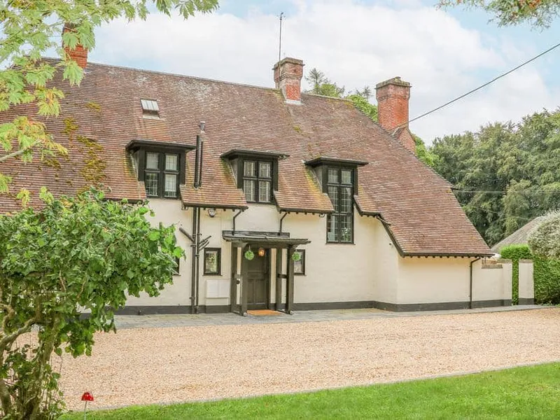 Little Picket cottage with steep tiled roof and gravel driveway in front garden.