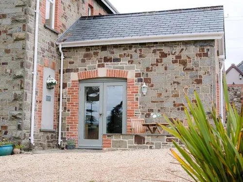 Cottage exterior with stone walls, patio door and small outdoor table with chairs