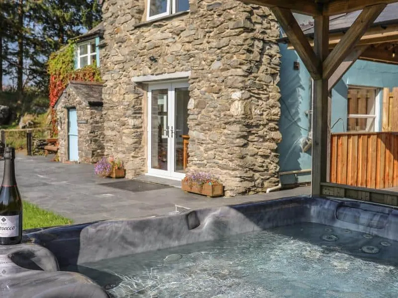 Stone cottage exterior with hot tub and Prosecco on the patio at Maes Madog.