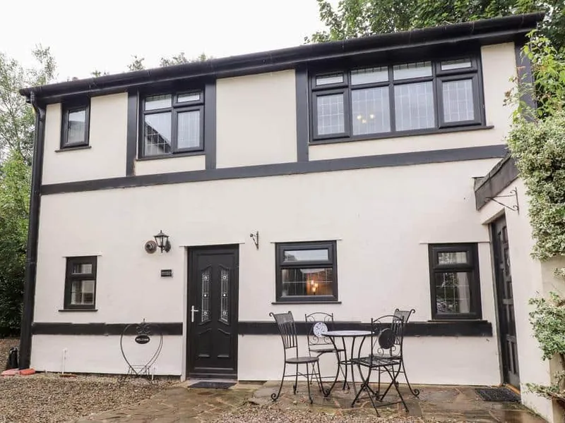 Mayfield Cottage exterior with black trim and a small patio table and chairs by the entrance.