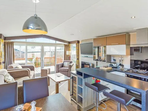 Lodge open-plan kitchen and living area with sofas, breakfast bar and patio doors
