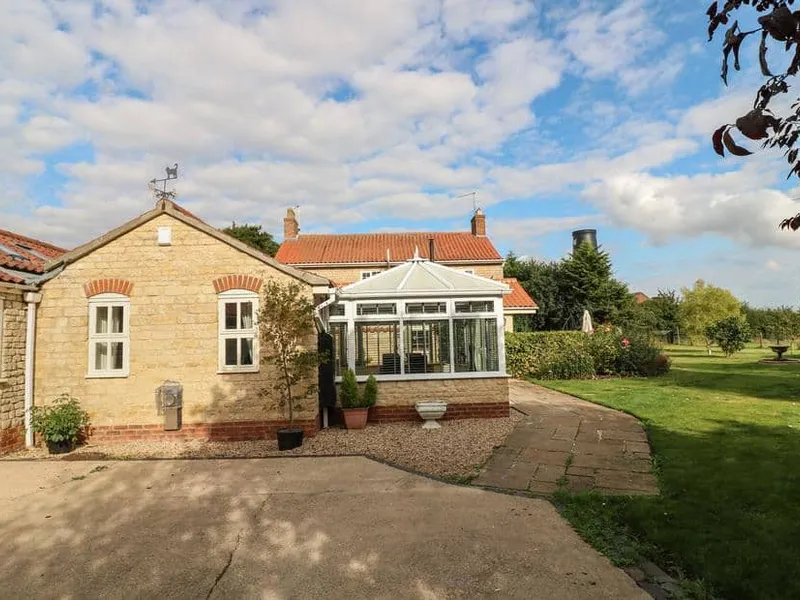 Millcott with conservatory overlooking a large garden lawn and patio area
