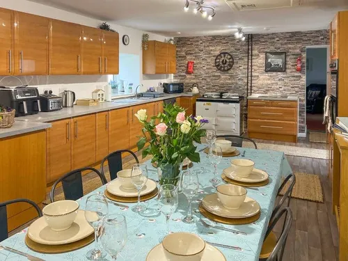 Cottage kitchen with dining table set for eight and wood cabinets