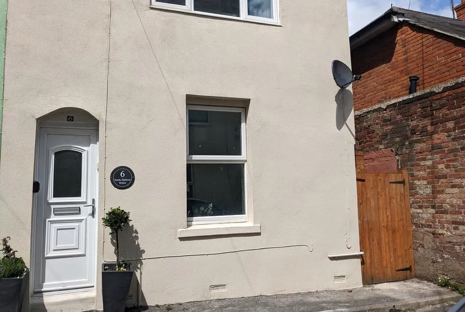 North Harbour House exterior with white door and window near brick wall and wooden gate