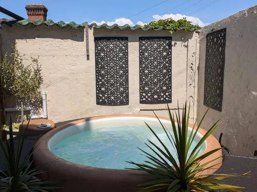 Cottage courtyard with circular hot tub and decorative wall panels