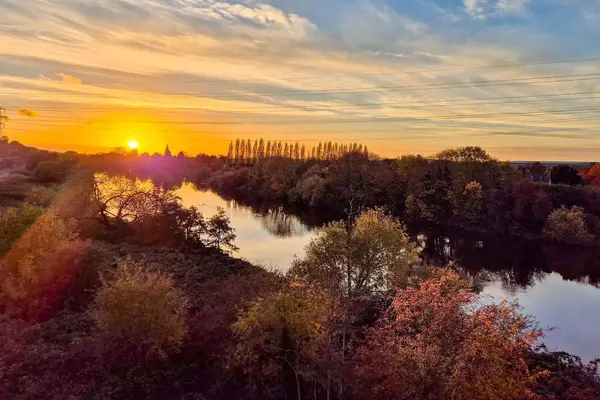 Sunset over the River Trent in Nottinghamshire, with trees reflecting on calm water.
