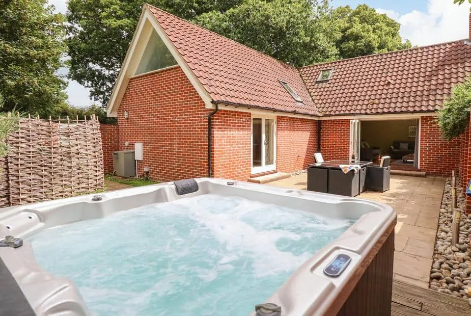 Oak Tree Lodge exterior with private hot tub on stone patio and open outdoor seating area