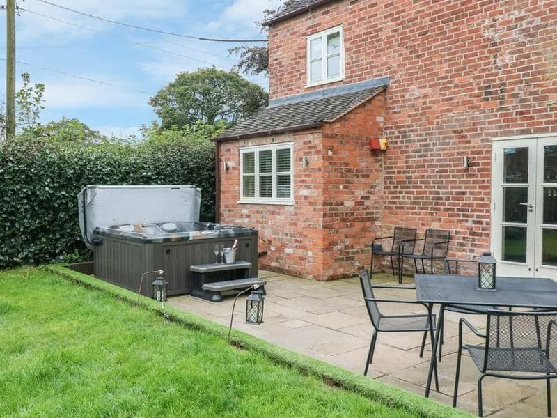 Orchard Barn brick exterior with outdoor hot tub and patio seating area