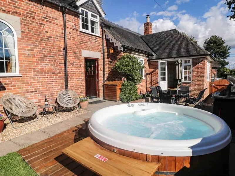 Orchard Cottage red-brick exterior with outdoor hot tub and patio seating