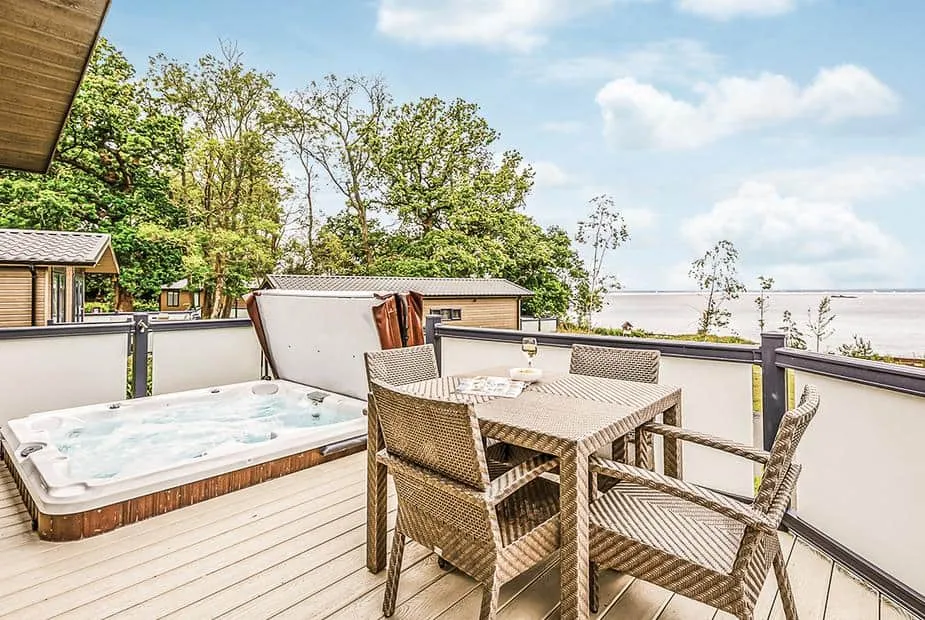 Deck at Osborne Premier Lodge with hot tub, outdoor dining set, and estuary views
