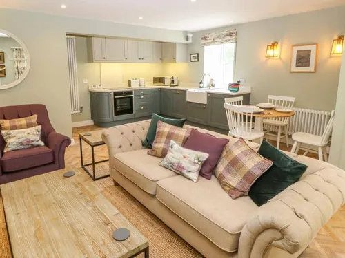 Cottage open-plan living area with sofa, armchair, kitchen and dining table