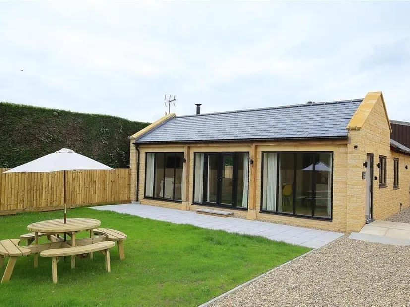 Park Bothy with large glass doors and a picnic table with umbrella in fenced garden