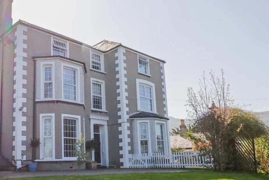 Penholm cottage exterior with large bay windows and white picket fence in front garden.