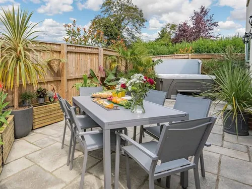 Cottage patio with dining set, potted plants and hot tub