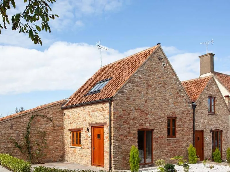 Poppy Cottage with stone exterior, red tiled roof, and small front garden