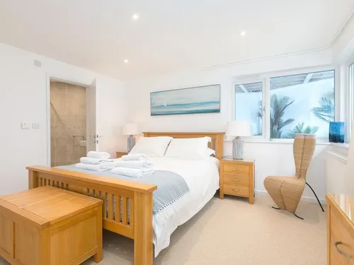 Cottage bedroom with wooden bed, side tables and window overlooking garden plants