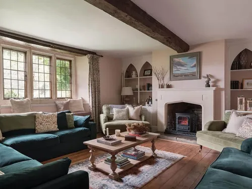 Cottage living room with sofas, wood burner and exposed ceiling beam
