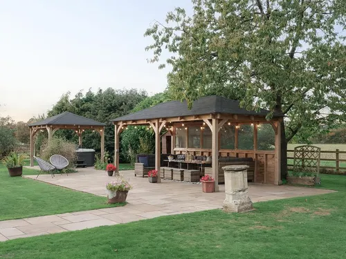 Covered patio seating area in garden with outdoor furniture and potted plants
