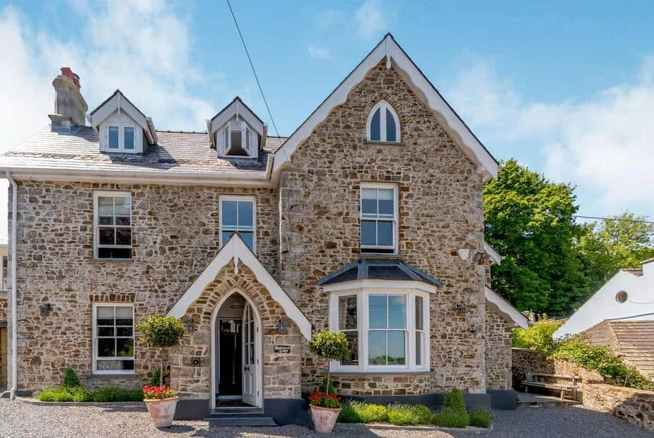 Rhodewood Lodge stone exterior with arched doorway and bay window facing the driveway