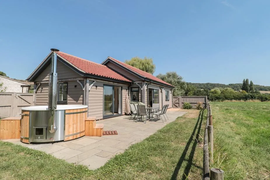 Robins Corner lodge with patio seating and outdoor hot tub overlooking open countryside.