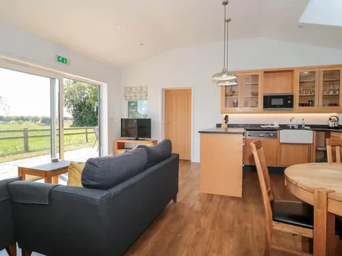 Lodge open-plan living area with sofa, kitchen, dining table and patio doors to outside