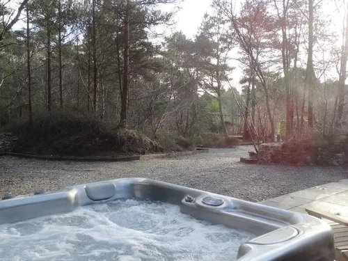 Hot tub on stone patio outside cottage with woodland views