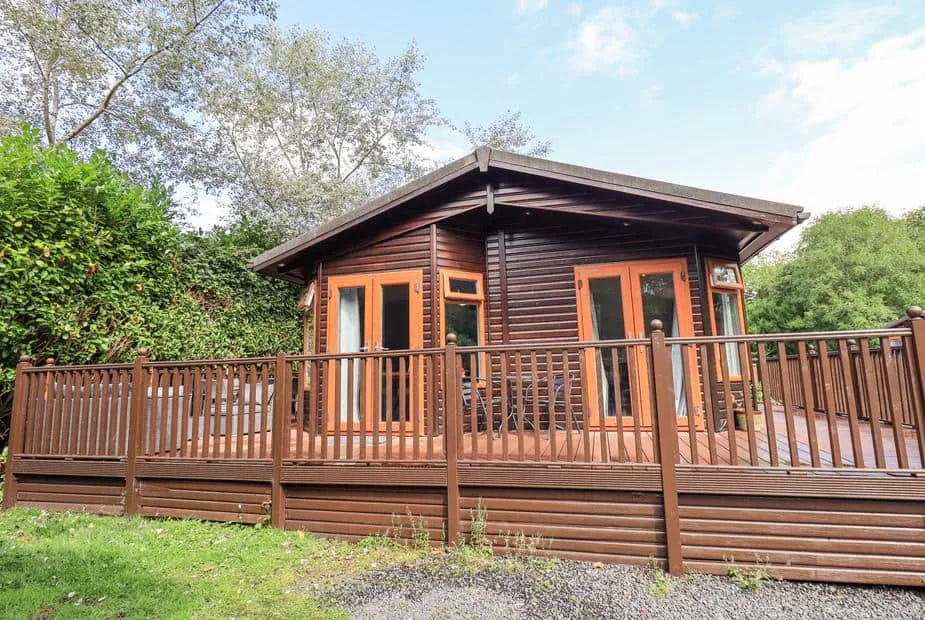 Rydal Lodge with raised decking and outdoor seating, surrounded by trees and greenery.
