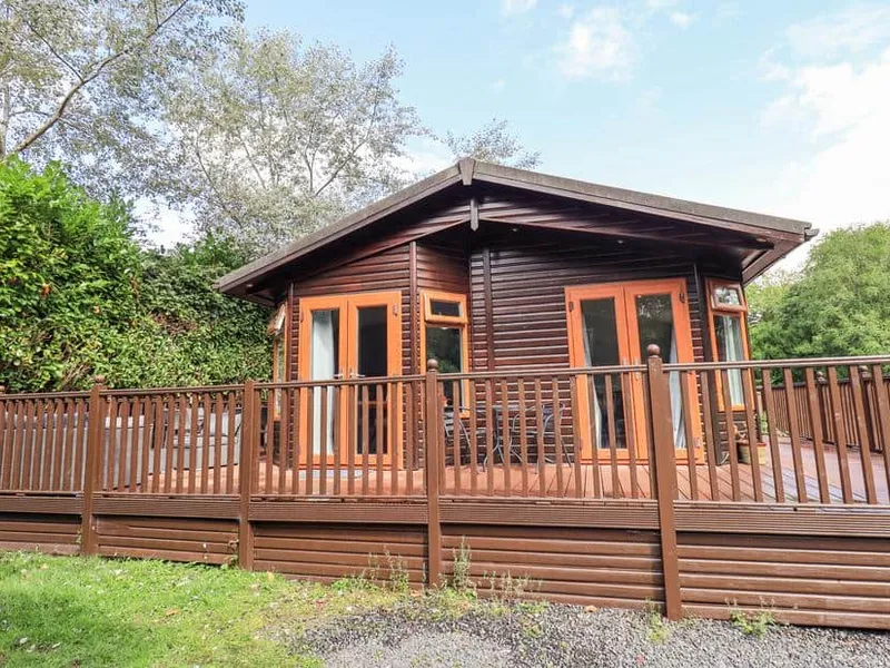 Rydal Lodge with raised decking and outdoor seating, surrounded by trees and greenery.