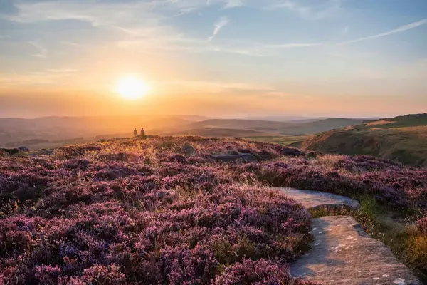 A couple enjoying a romantic sunset from Higger Tor, the iconic Peak District landscape on Sheffield's doorstep.